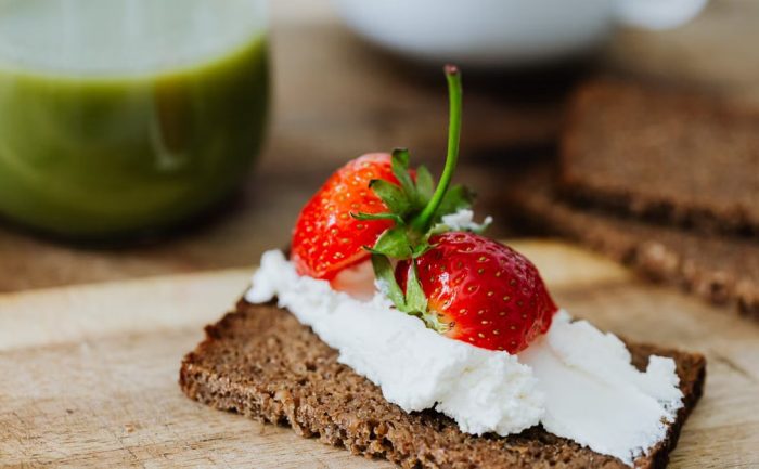 Rye bread topped with cream and juicy strawberries, perfect for a sweet treat.